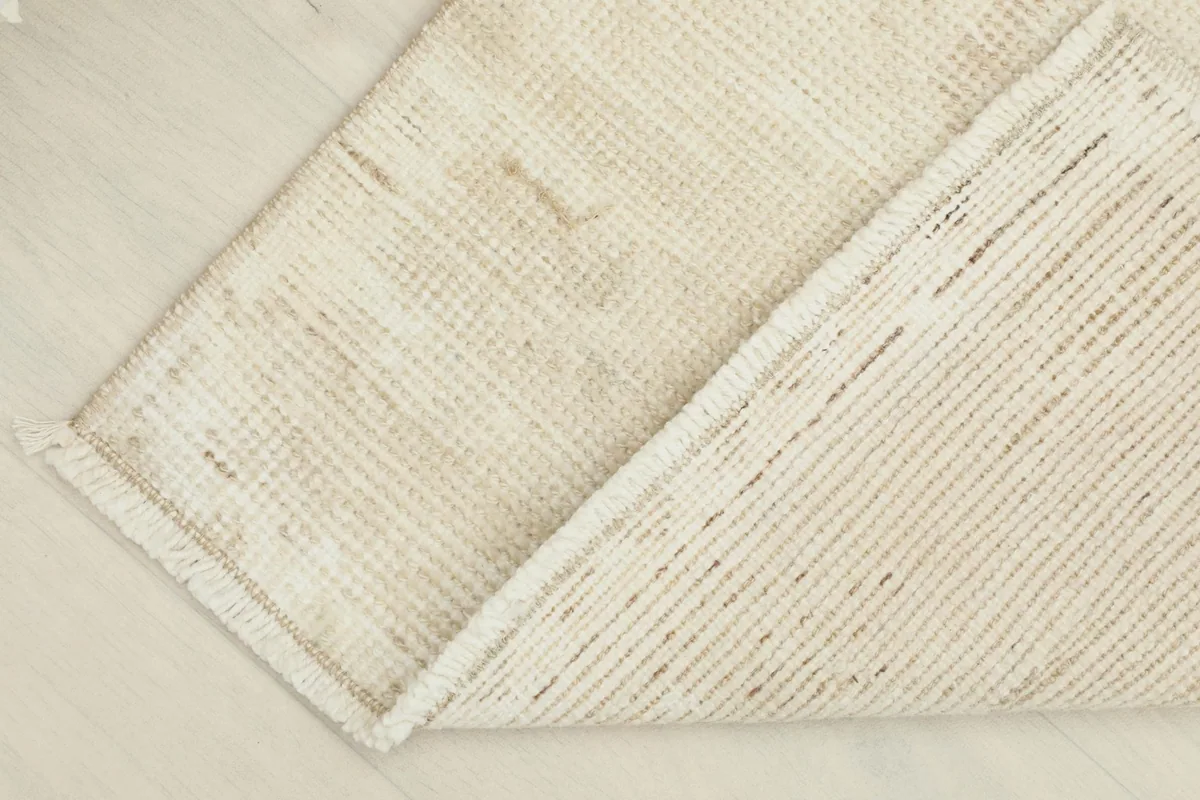 View of the rug's reverse side and cotton foundation, demonstrating its hand-knotted craftsmanship.