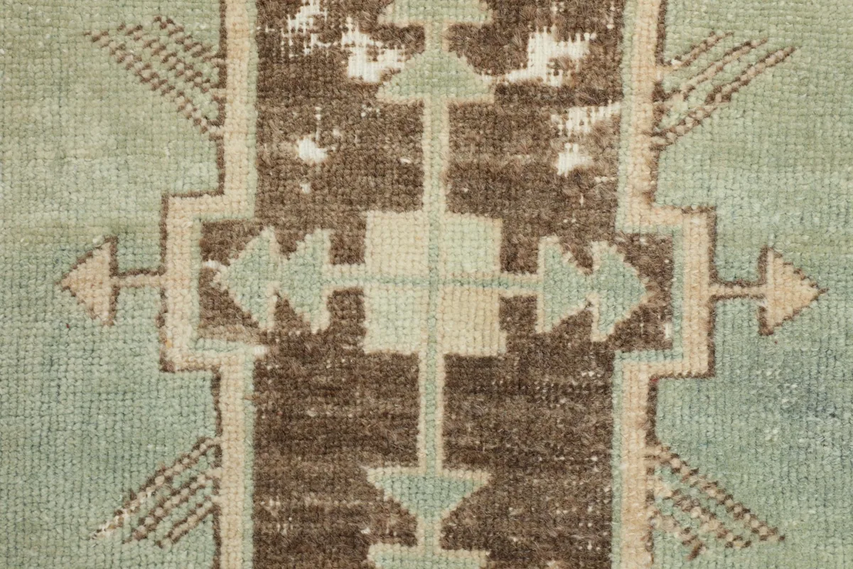 Zoomed-in shot of the intricate brown and green tribal patterns within the rug's center.