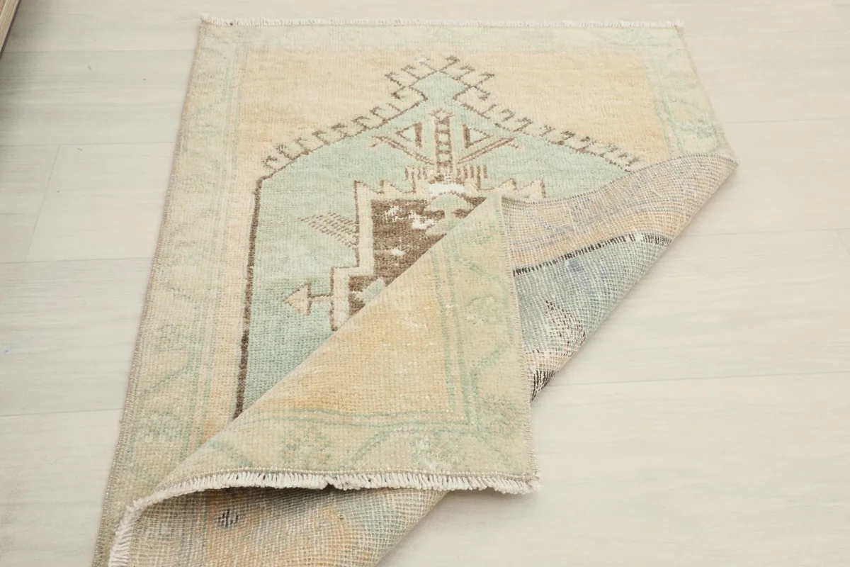 The rug partially folded, revealing the back side and the texture of the hand-knotted construction.