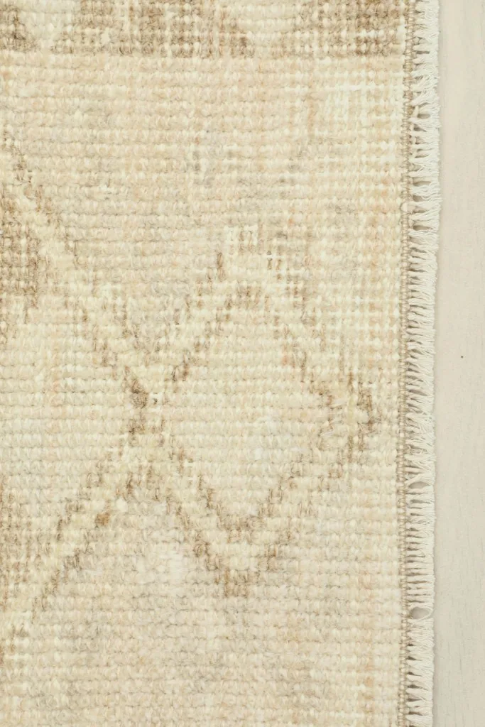 Close-up detail of the cream field and brown geometric lines, showing the texture and low pile of the vintage rug.