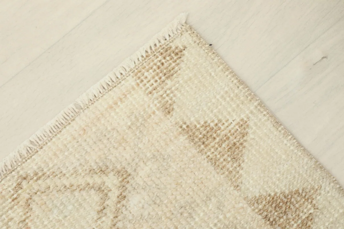 Corner detail showing the finished edge of the rug, with a subtle brown triangular border pattern.