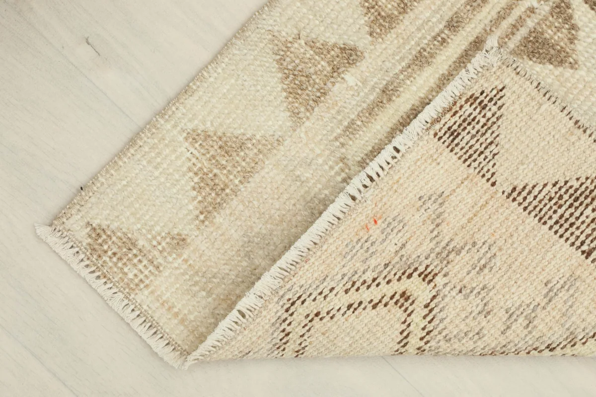 Rug corner folded back, revealing the cotton foundation and the reverse side of the hand-knotted wool pile.