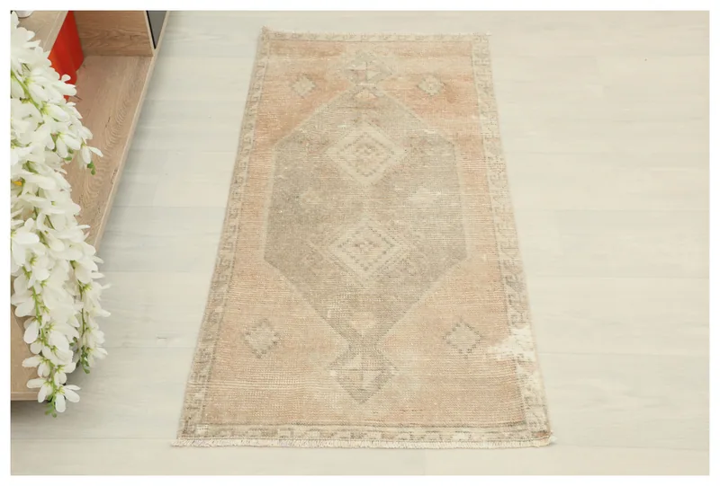Full overhead view of the rust and beige vintage Anatolian doormat on a white background.