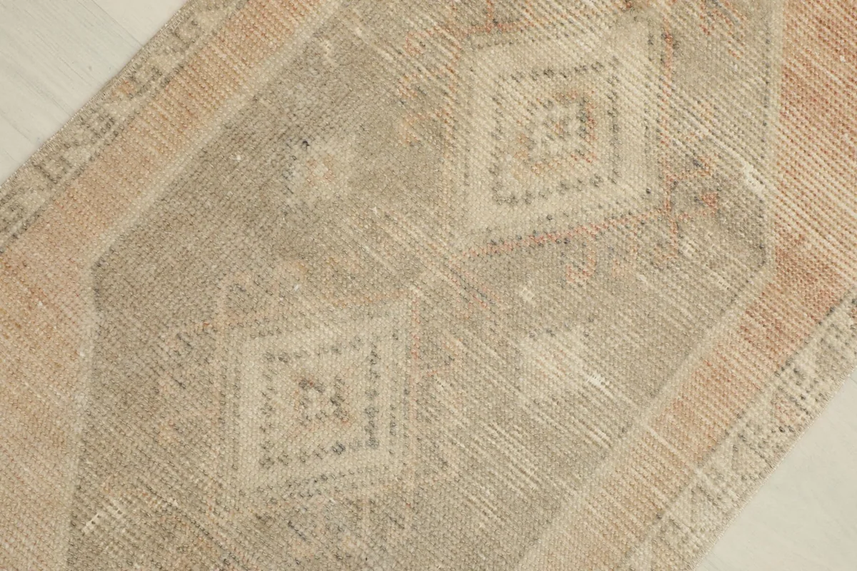 Detailed view of the central beige and gray geometric patterns within the rug's design.