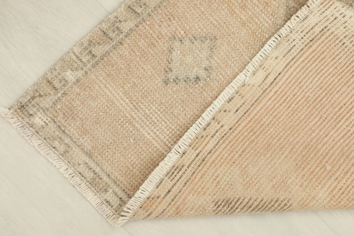 View of the underside of the rug, showing the cotton foundation and the reverse of the hand-knotting.