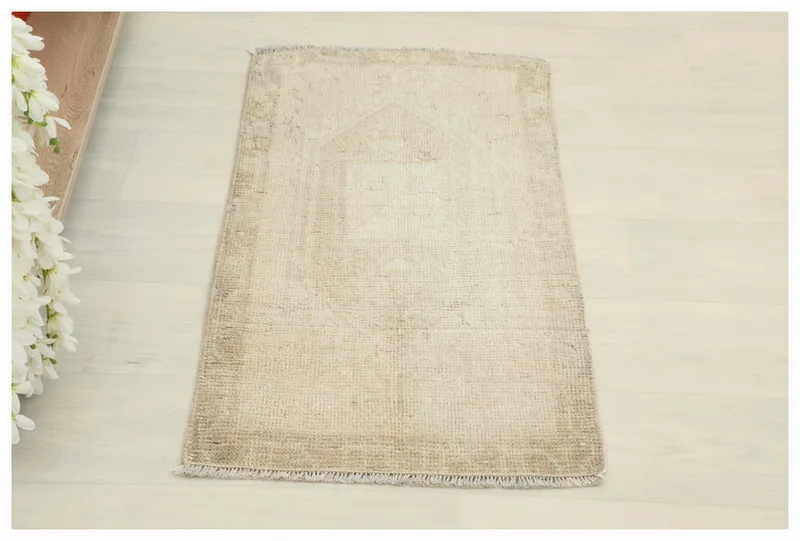 Full top view of the vintage beige geometric Anatolian doormat rug on a white floor.