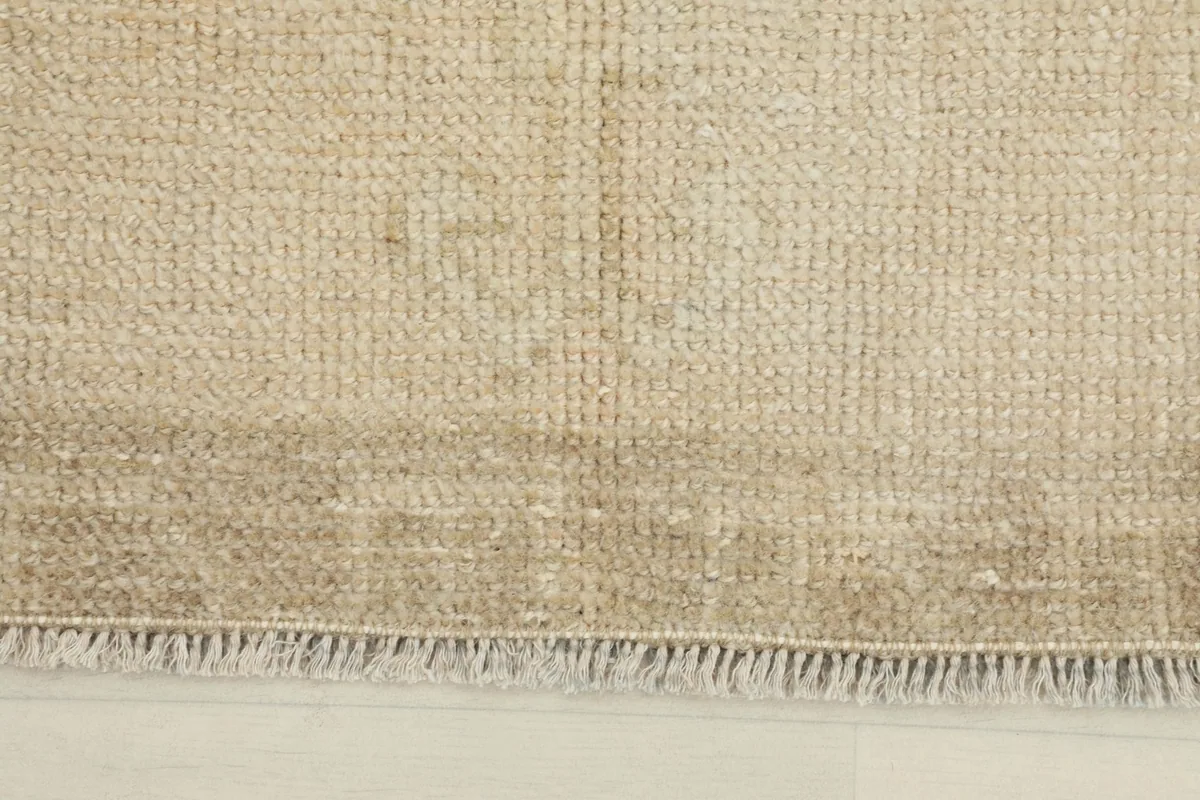 Close-up detail of the rug's texture and fringe, highlighting the wool pile and natural wear.