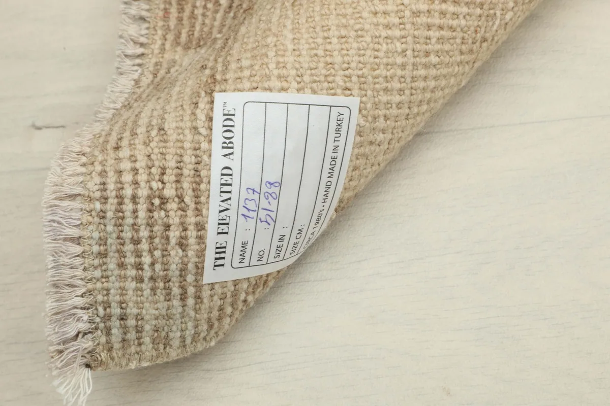 Close-up of the rug's reverse side, revealing the woven cotton foundation and a product label.
