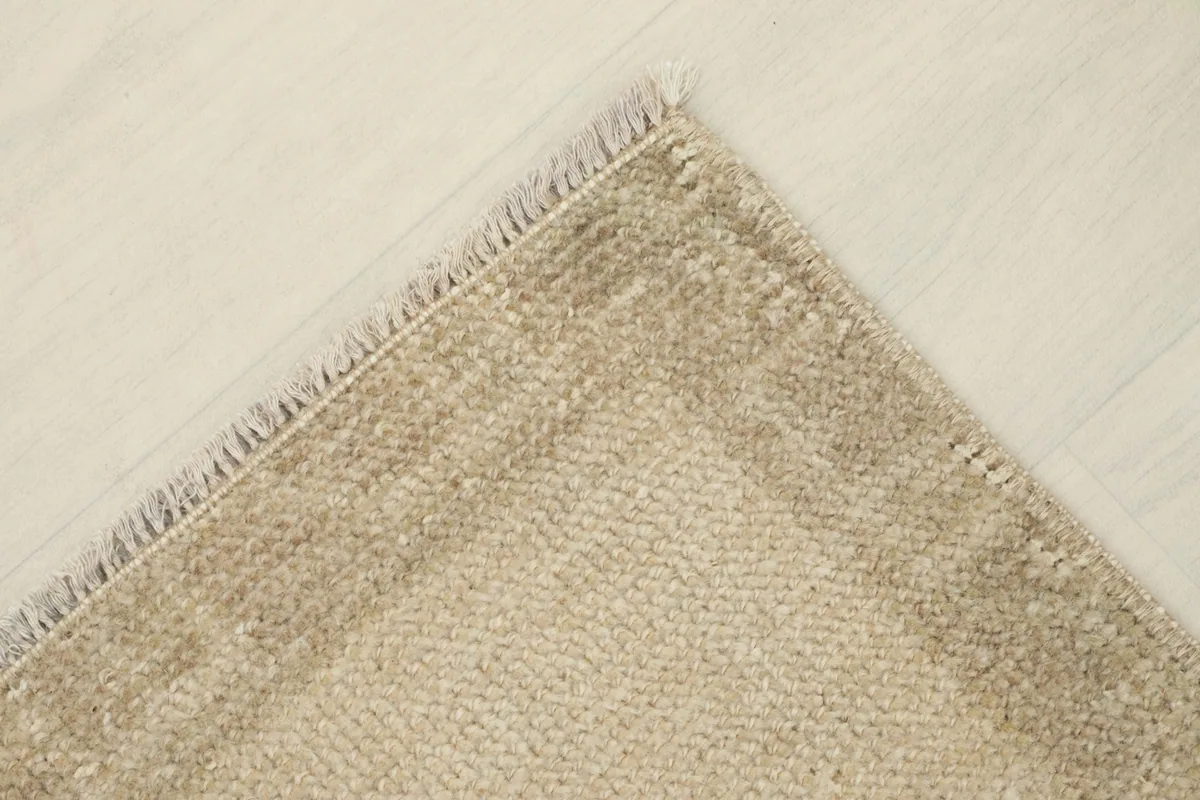 Overhead view of a rug corner, emphasizing the fringe and the subtle border design.