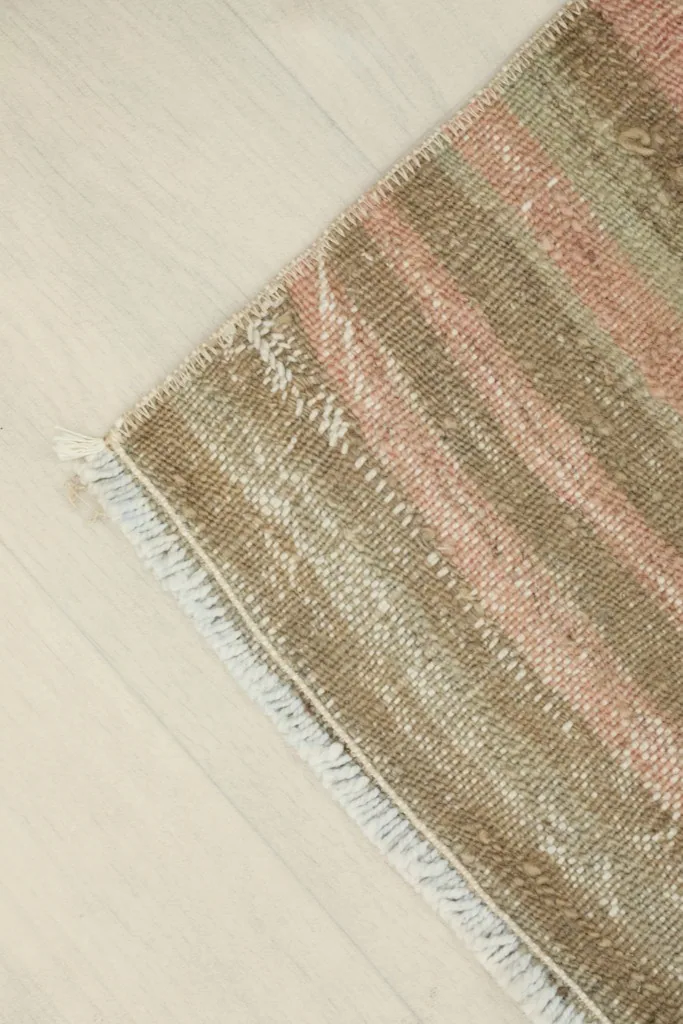 Angled close-up of a rug corner, emphasizing the vintage character and slight wear.