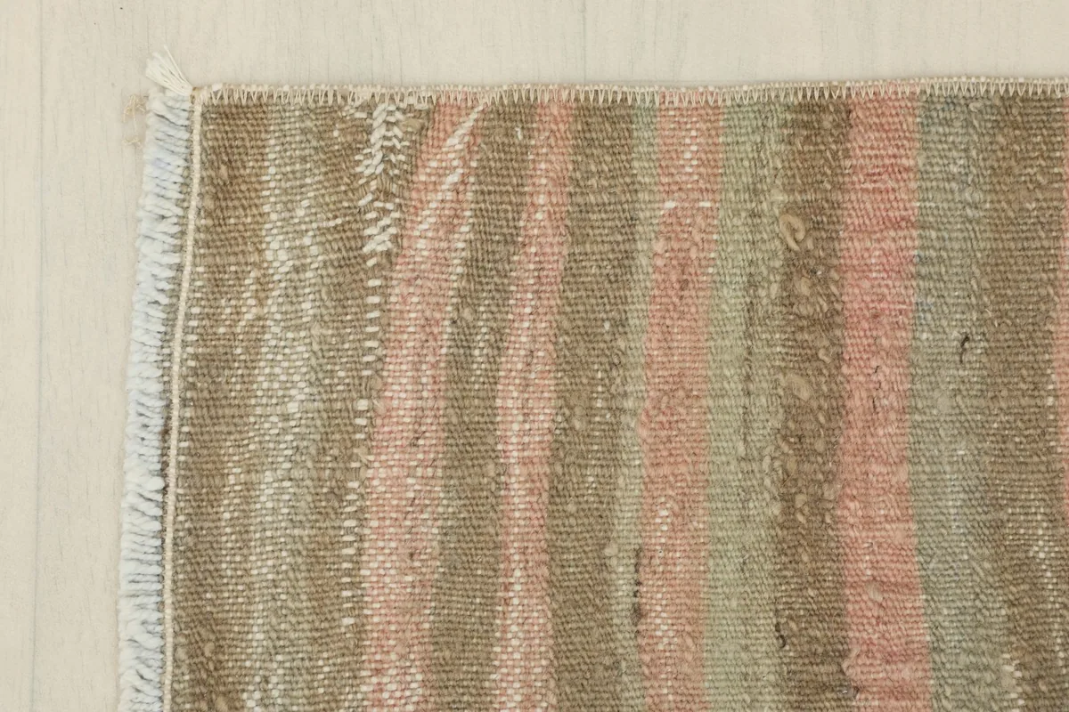 Corner view of the rug, showing the edge finish and the transition of the striped pattern.