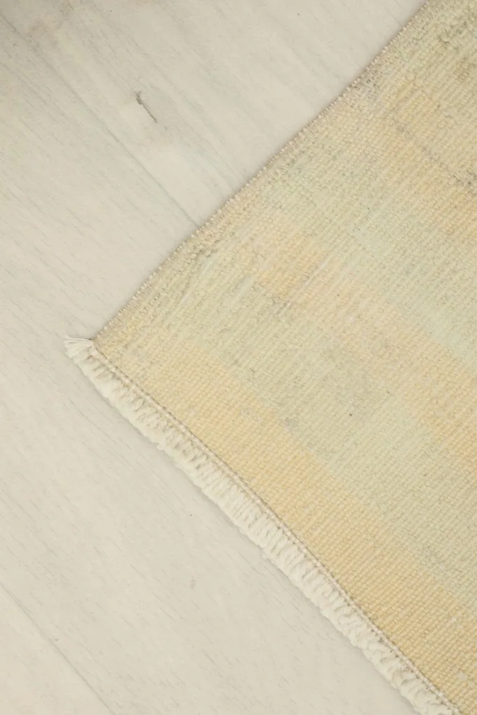 Angled view focusing on a corner of the rug, revealing the low pile and slight wear.