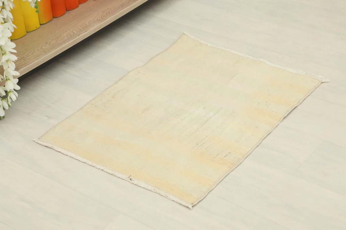 Angled view of the small cream vintage rug on a light floor, showing its placement potential.