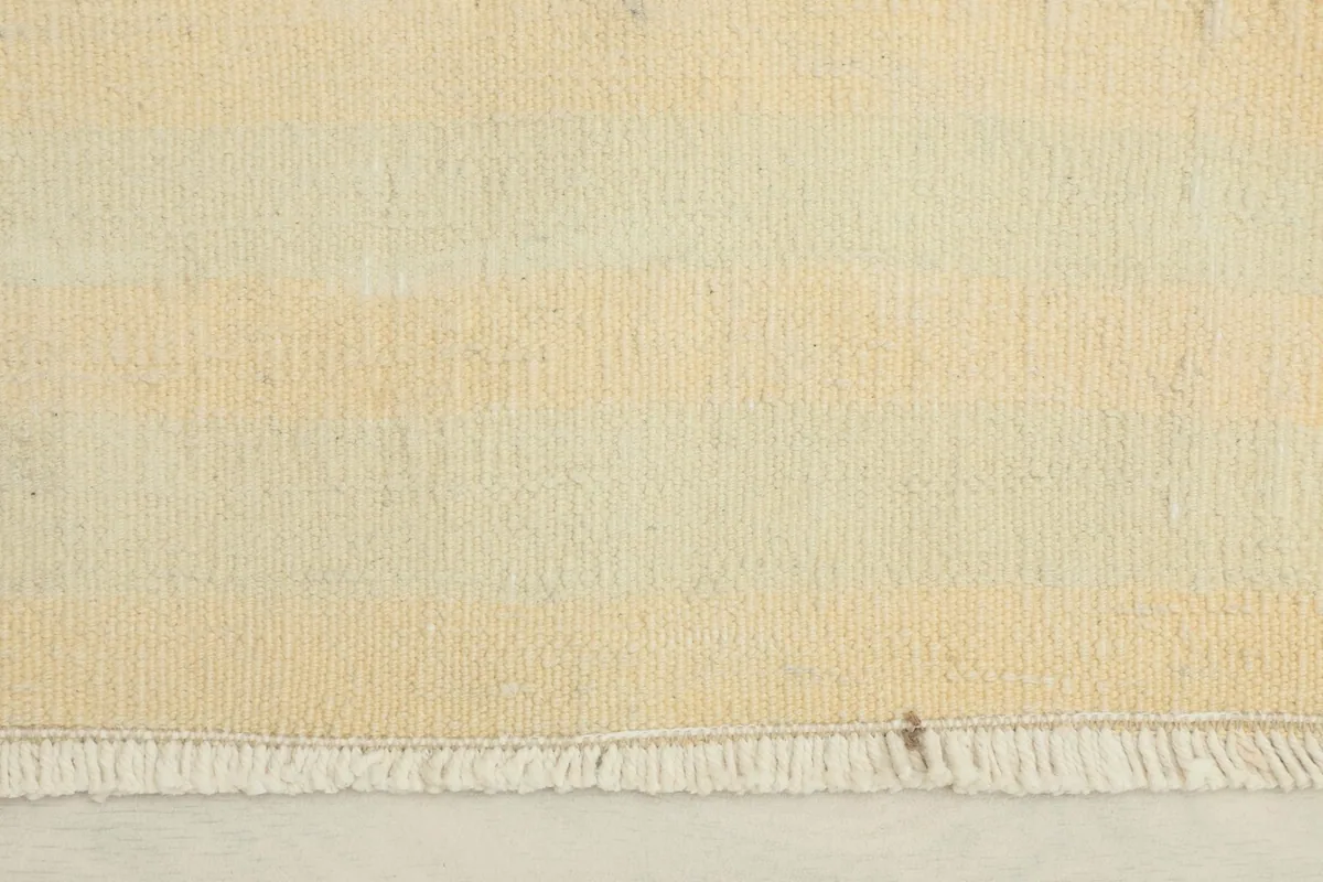 Close-up detail of the hand-knotted wool pile and subtle striped pattern in cream and beige tones.