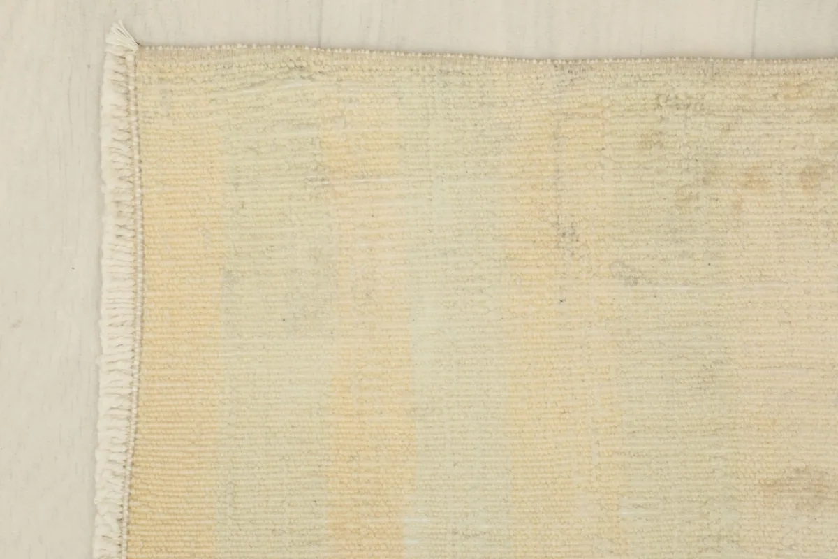 Corner detail of the rug, showing the edge finish and the short, natural fringe.
