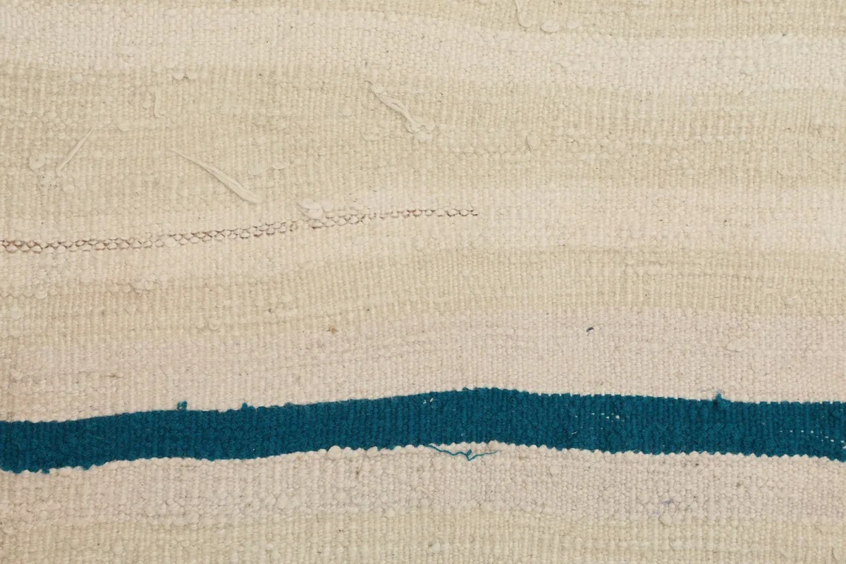 Detailed view of a blue stripe against the textured ivory and beige wool pile.