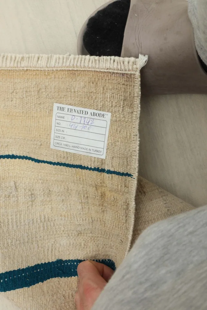Close-up of the rug's back, showing the hand-knotted structure and a product label.