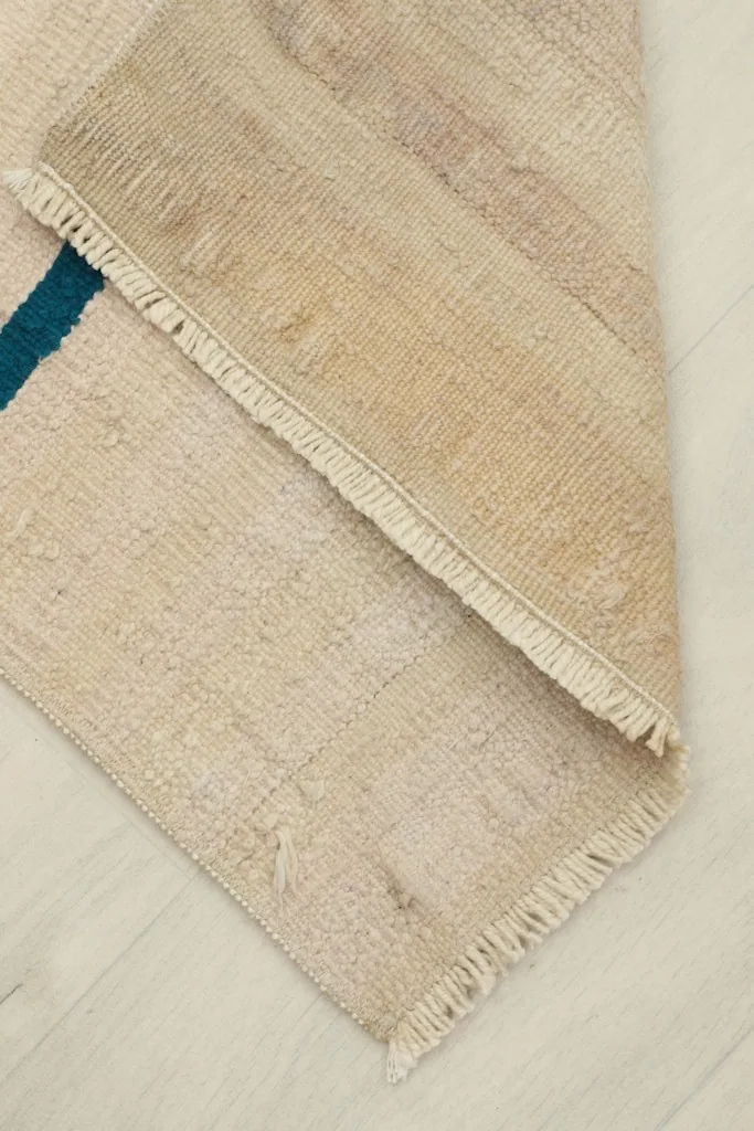 View of the rug partially folded, revealing the reverse side and the hand-knotted cotton foundation.