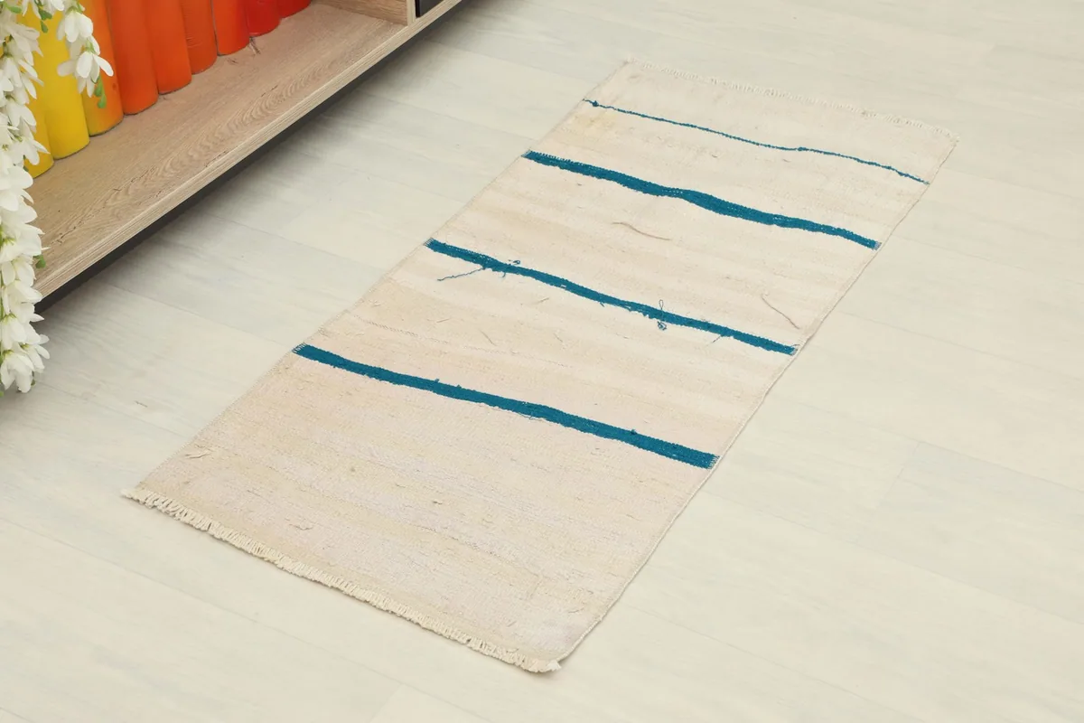 Slightly angled overhead view of the ivory and blue striped vintage rug on a light floor.