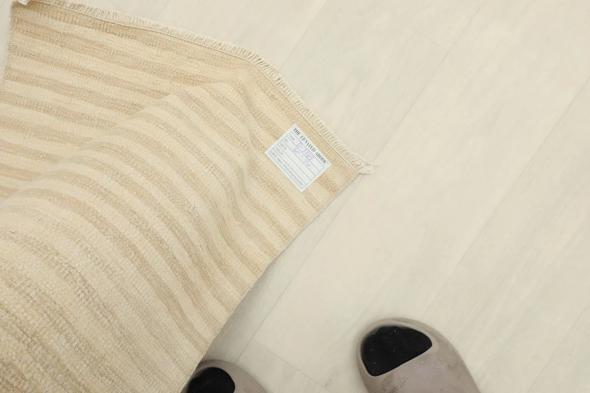 Overhead view of the rug with feet nearby, showing its scale and the label on the back.