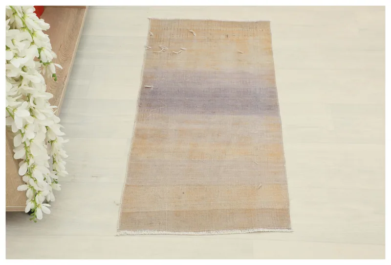 Full overhead view of the beige and purple distressed vintage Anatolian area rug on a white background.