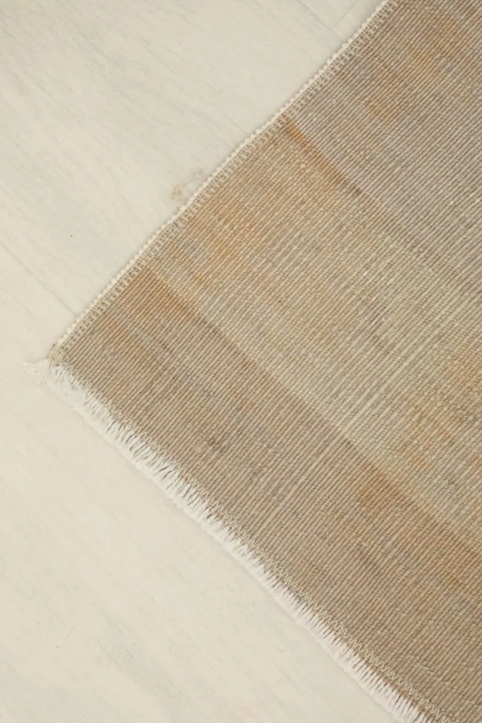 Angled view of a rug corner, emphasizing the low pile and the subtle color shifts.