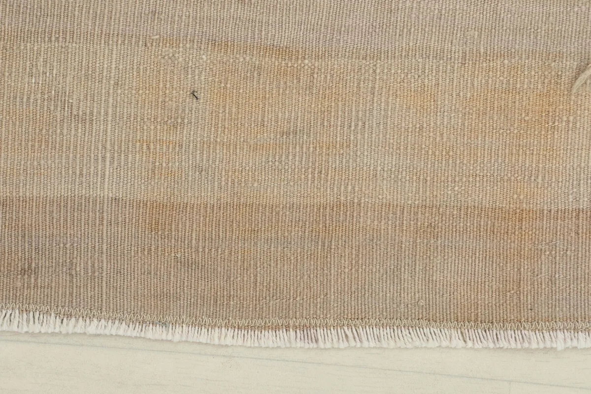 Close-up of the rug's surface, highlighting the subtle stripe pattern and muted beige tones.