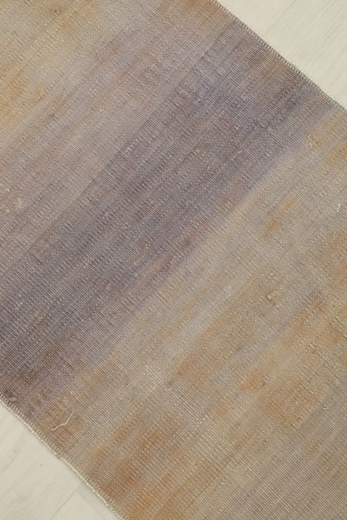 Detail view focusing on the transition from beige to purple and gray tones in the rug's design.