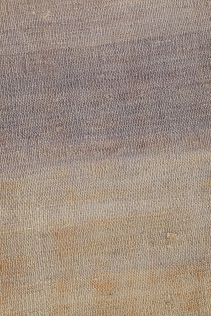 Close-up of the central area of the rug, showing the blend of purple, gray, and tan fibers.