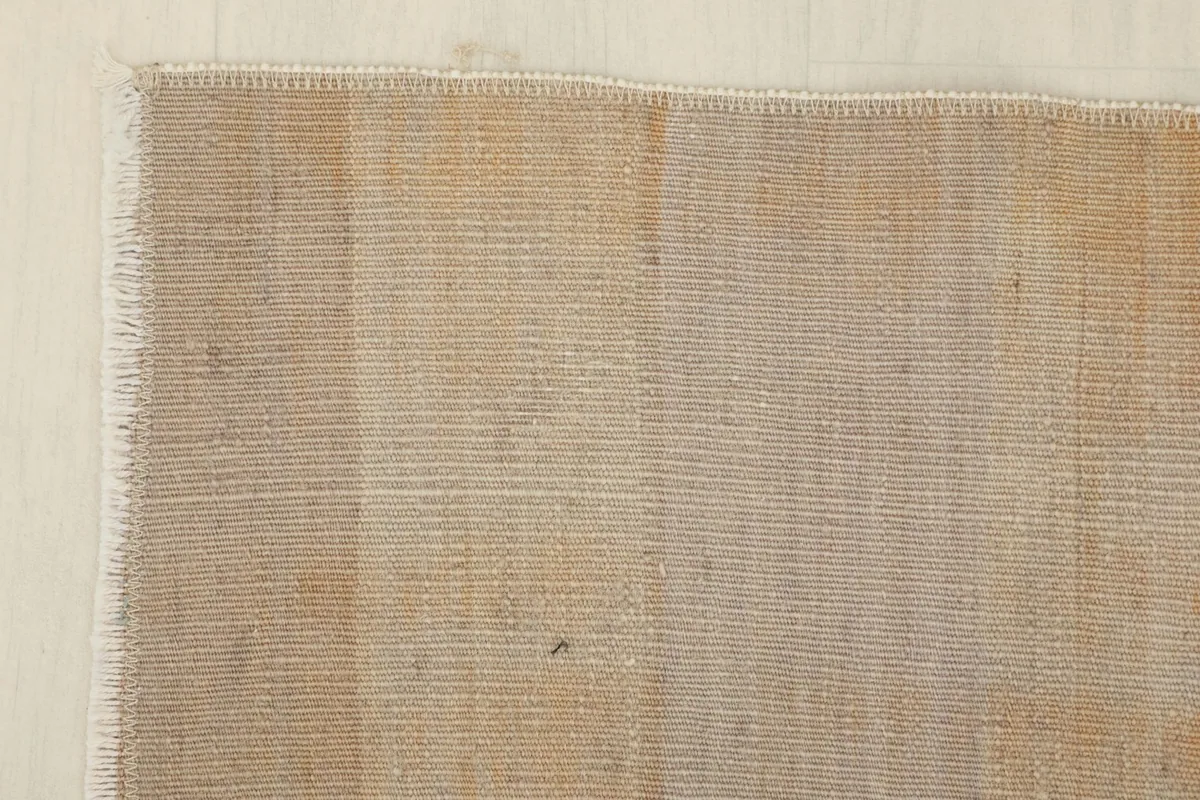 Corner detail of the rug, showing the finished edge and the tight weave of the wool pile.