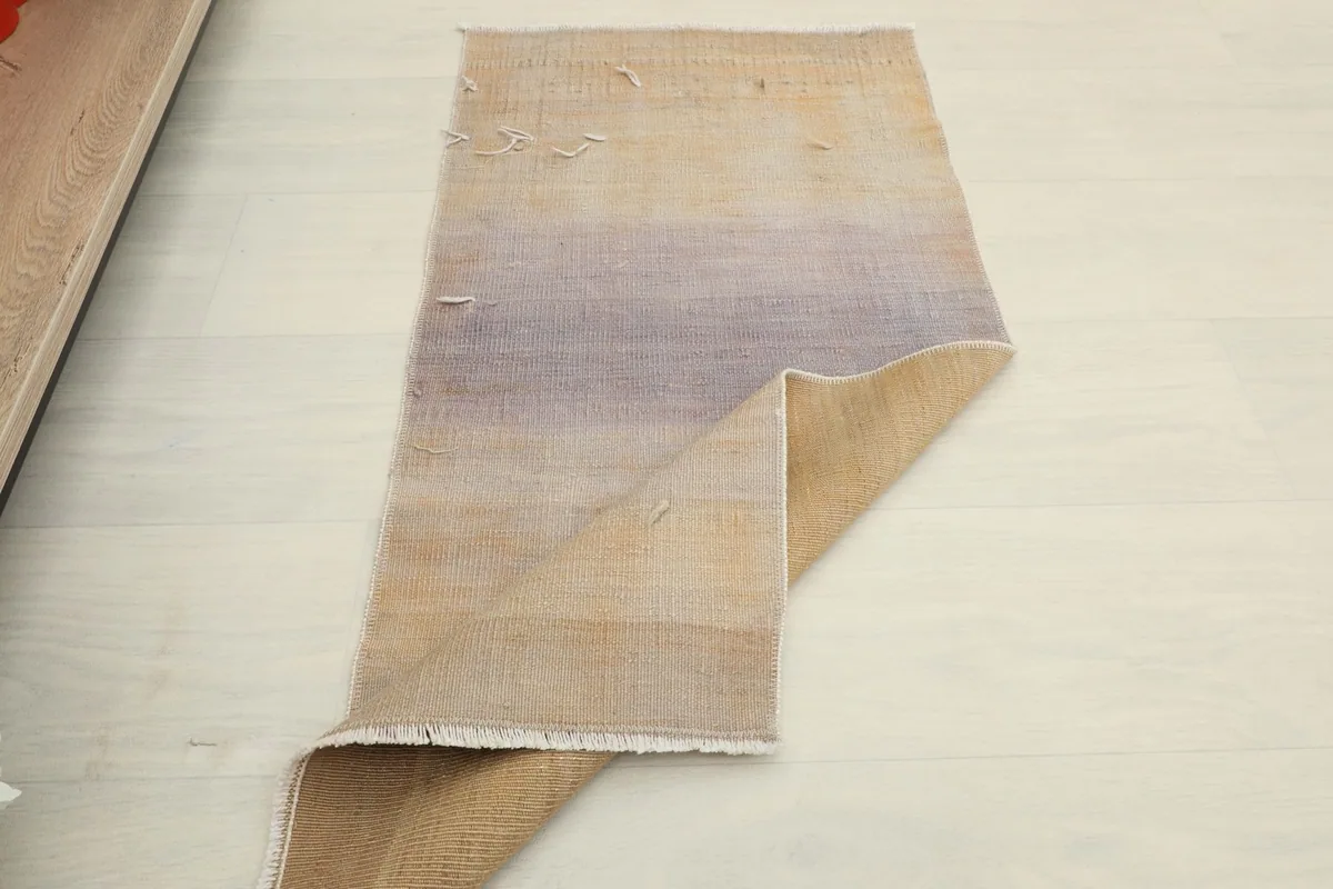 The rug partially folded, showing the flexibility and the reverse side with its cotton foundation.