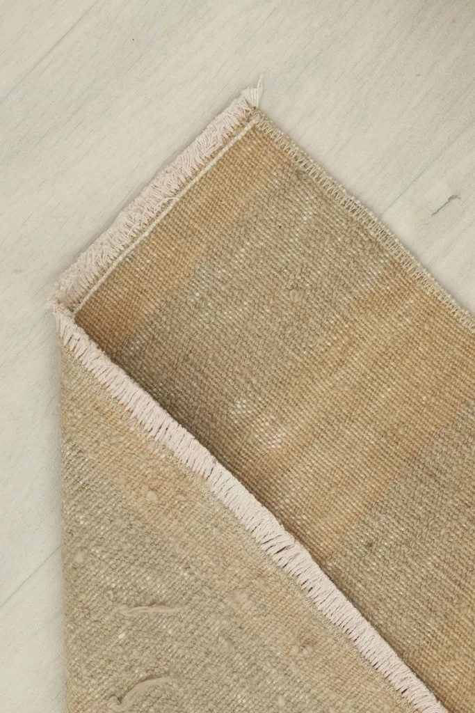Corner view of the rug folded to show the cotton foundation and the reverse side.