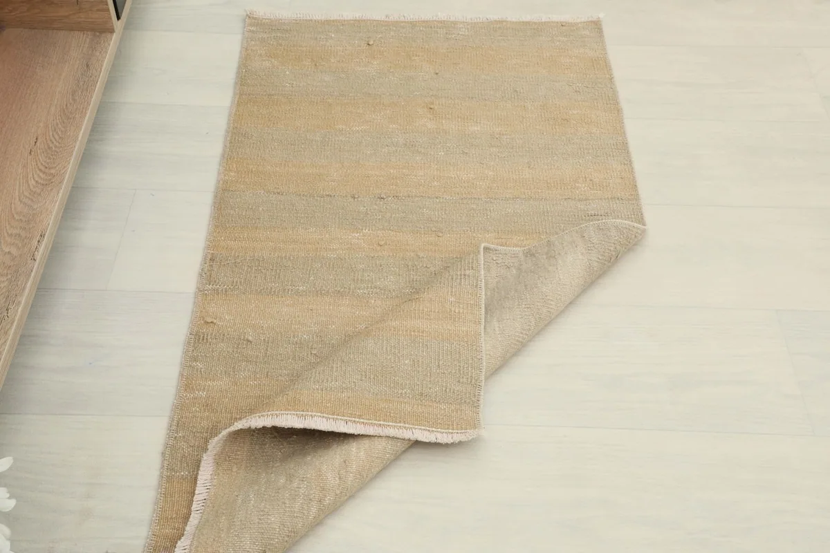 Overhead view of the rug with one corner folded back, revealing the reverse side.