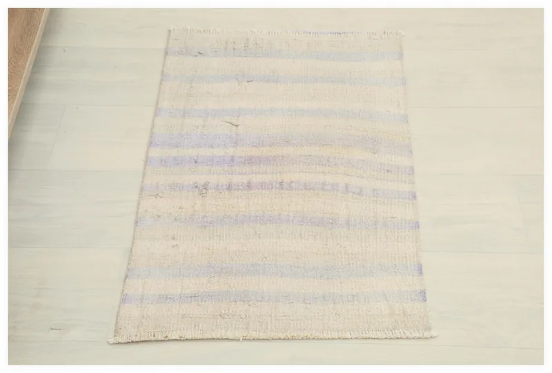 Full top view of the ivory and purple striped vintage Anatolian doormat on a white background.