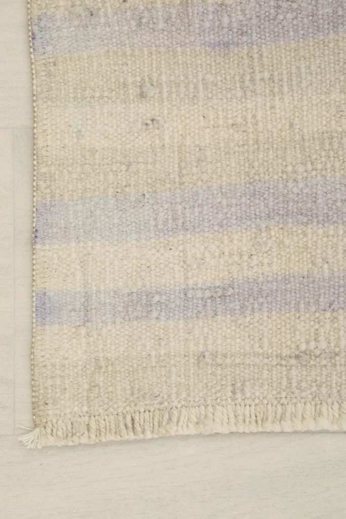 Detail shot of the rug's corner, highlighting the subtle color variations and hand-knotted construction.