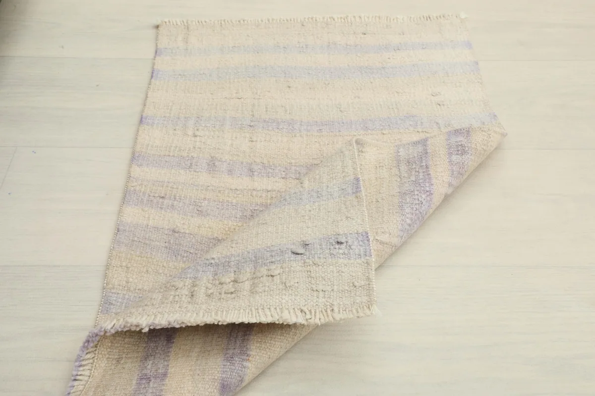 The rug partially folded, displaying its flexibility and the natural drape of the wool fabric.