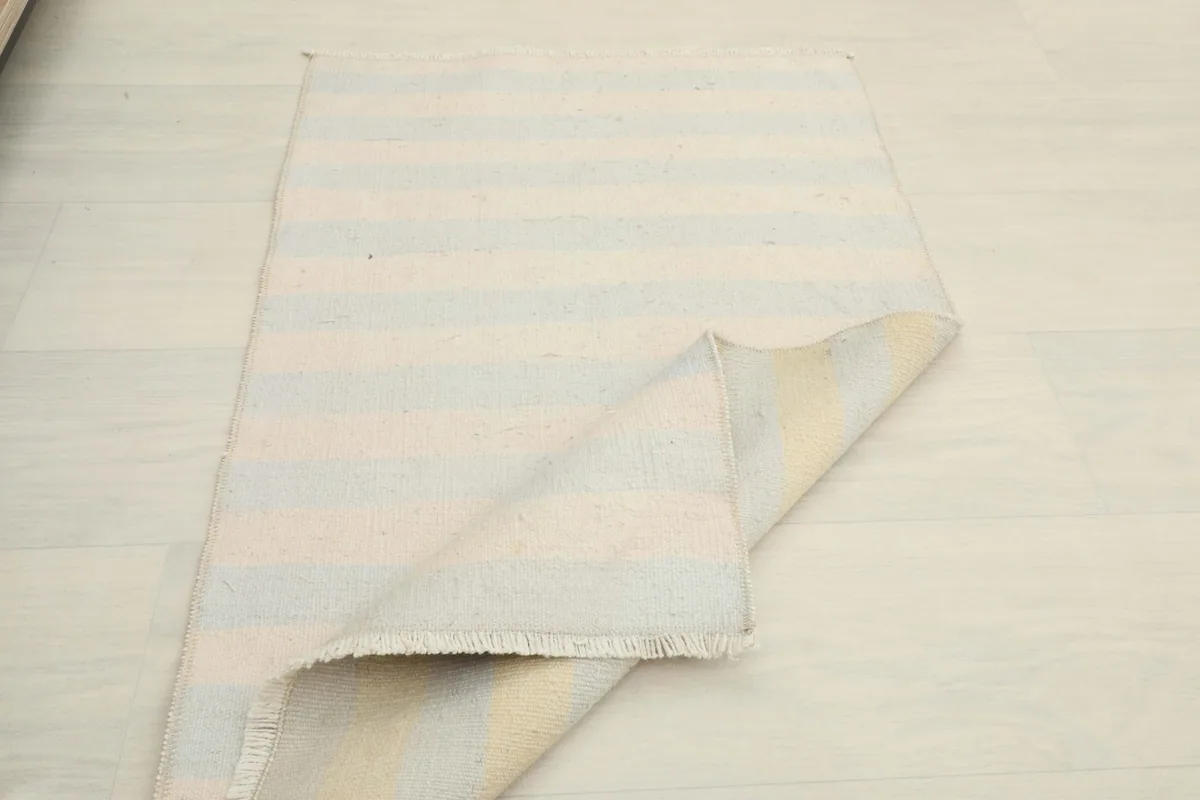 Rug partially folded, displaying the back and front of the striped design.