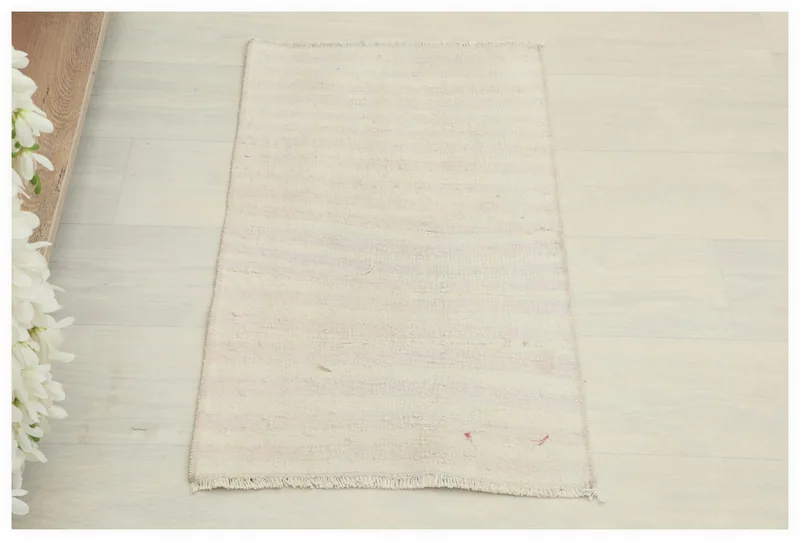Top view of a cream and rose minimalist vintage Anatolian wool rug on a white floor