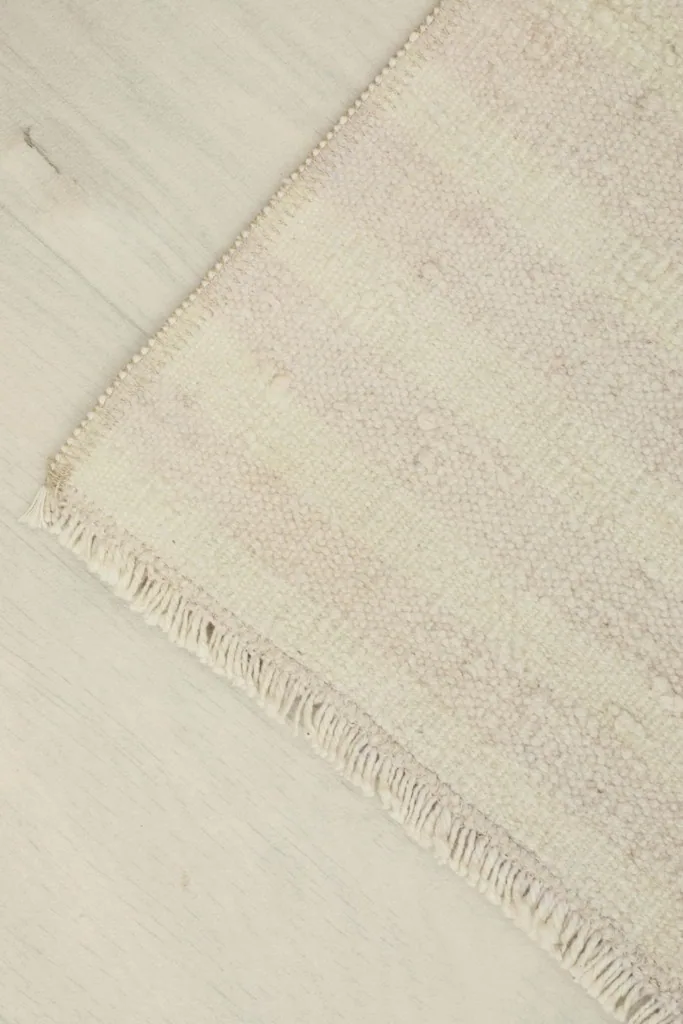 Corner view of the hand-knotted rug, displaying the low pile and simple finish