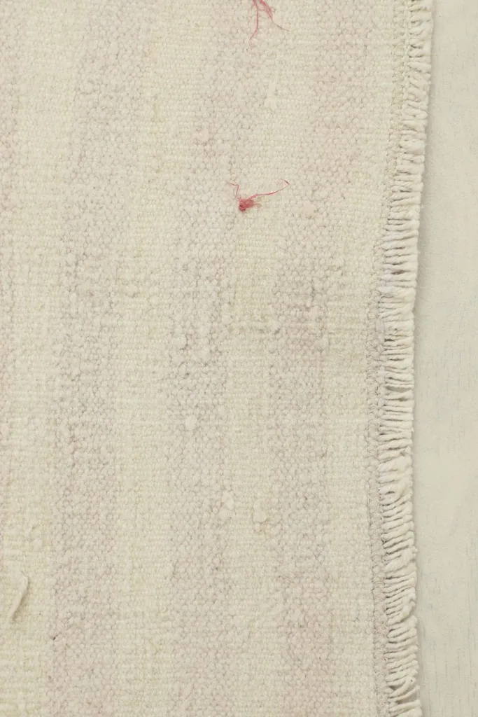 Close-up detail of the cream pile and subtle rose stripes, showing texture and fringe