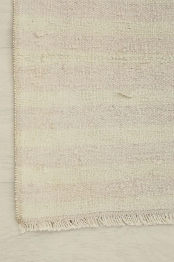 Close-up of the rug's edge, showing the subtle striped pattern and short fringe