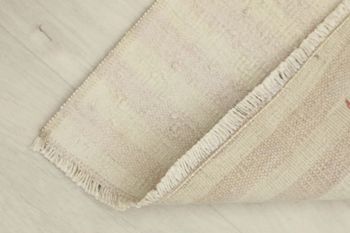 View of the rug folded, revealing the back of the rug and the cotton foundation
