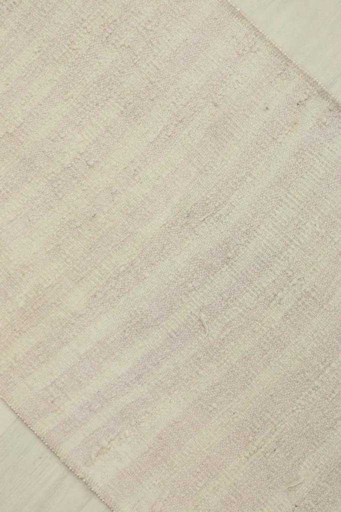 Overhead angled view of the cream and rose rug, showing its rectangular shape and texture