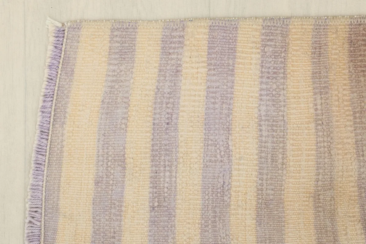 Overhead view focusing on a section of the rug, detailing the consistent purple and ivory striped design.