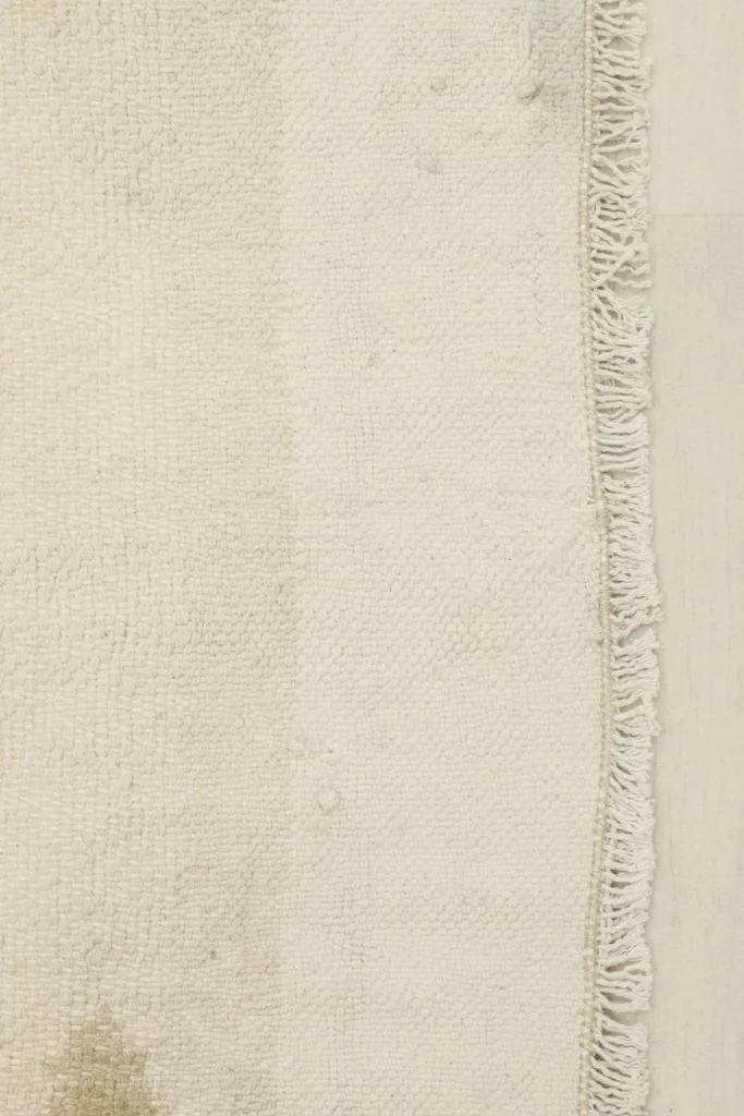 Close-up of the rug's texture, showing the beige and ivory stripes and fringe detail.