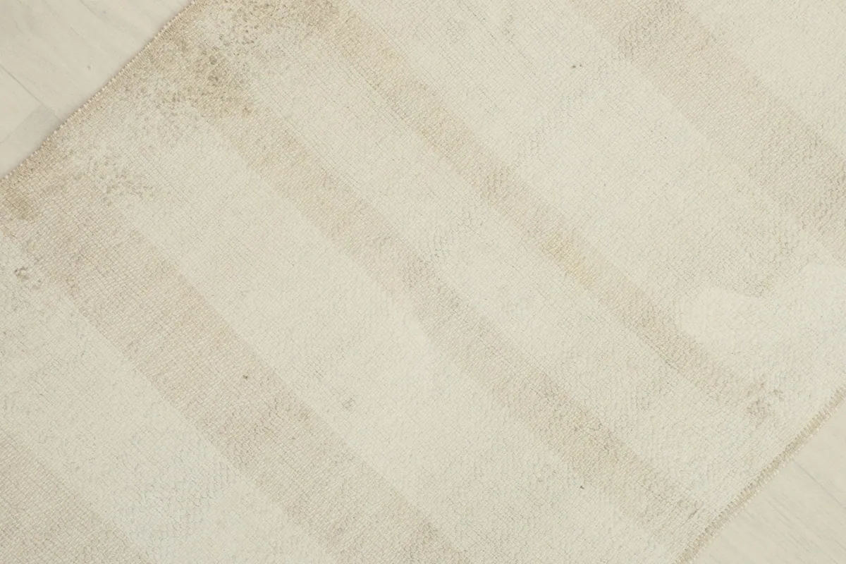 Detailed angled view highlighting the subtle striped pattern and vintage patina on the rug's surface.