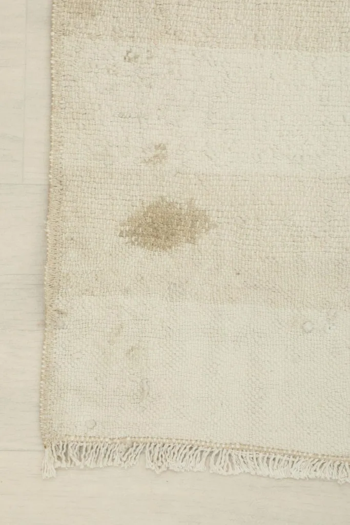 Close-up of a noticeable brown spot and general wear, indicating the rug's vintage character.