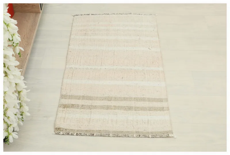 Full overhead view of the beige and gray striped vintage Anatolian rug on a white floor