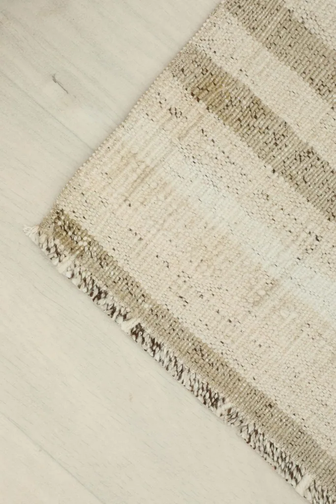 Corner detail of the rug, highlighting the fringed edge and striped design