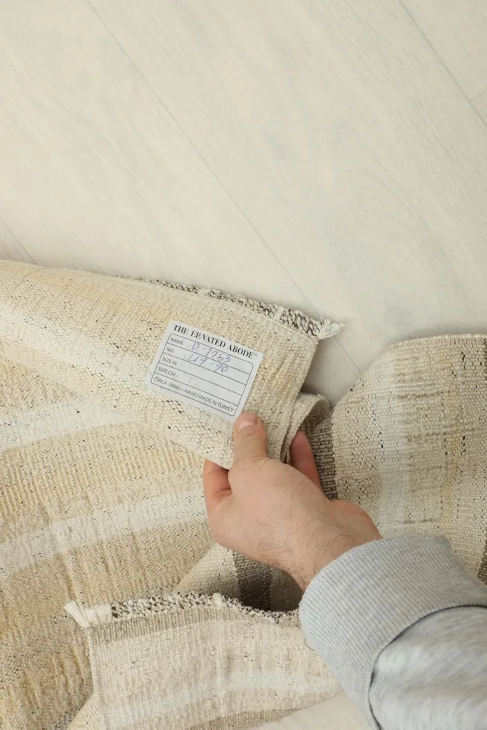 A hand holding the label on the back of the hand-knotted vintage Anatolian rug
